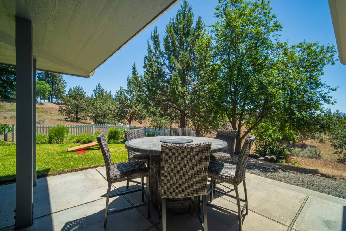 A fenced yard surrounds an inviting outdoor dining set among lush greenery. The area is ideal for al fresco dining, family-style meals, or unwinding with friends after exploring local attractions.