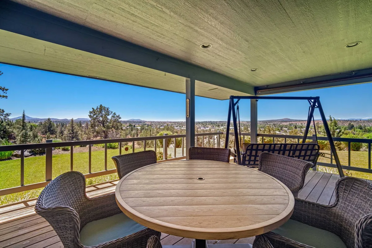A circular wooden table and a swing seat are positioned to take full advantage of the expansive landscape views. The scene is communal, emphasizing relaxation, outdoor dining, and stargazing opportunities under the wide-open sky.