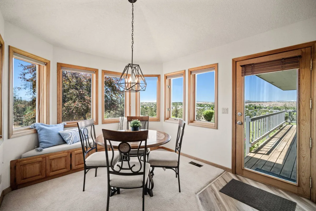 A cozy dining area centered around a round table, flanked by large windows and a window seat that invite in natural light and stunning sunrise views. The elegant chandelier adds a touch of warmth, making the space perfect for family meals or morning coffee with a view.